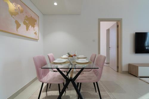 a dining room with a glass table and pink chairs at Modern 1-bedroom apartment in family-friendly residence with Swimming Pool, Gym & Free Parking. in Dubai