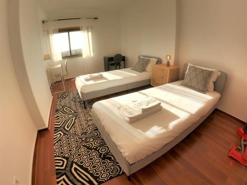 a bedroom with two beds and a rug at Lisbon T2 apartment in condominium in Linda-a-Velha Oeiras Lisbon in Linda-a-Velha