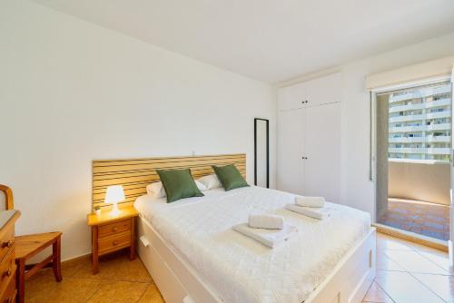 a white bedroom with a large bed with green pillows at Benalbeach playa - Tu hogar frente al mar, complejo 4 piscinas in Arroyo de la Miel