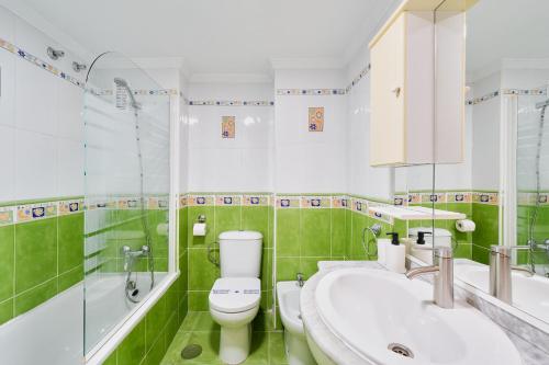 a green bathroom with a toilet and a sink at Benalbeach playa - Tu hogar frente al mar, complejo 4 piscinas in Arroyo de la Miel
