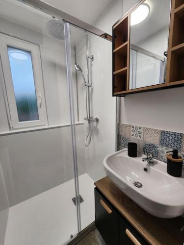 une salle de bain blanche avec un lavabo et une douche dans l'établissement Marmoza - Maison plein cœur de village, à Saint-Geniez-dʼOlt
