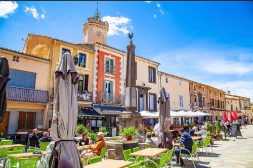 une place de ville avec des tables et des parasols et une tour de l'horloge dans l'établissement T2 climatisé front de mer avec terrasse et parking - V0742, à Vias