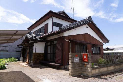 a brown and white house with a fence at 木の家ゲストハウス4号館 in Mito