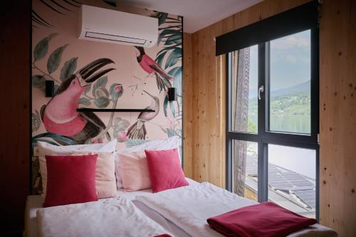 1 dormitorio con 1 cama con almohadas rosas y un mural de aves en Kantor Lodges & Chalets, en Millstatt
