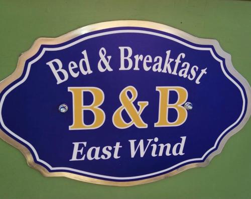 a blue sign for a bed and breakfast bed and board at East Wind in Medea