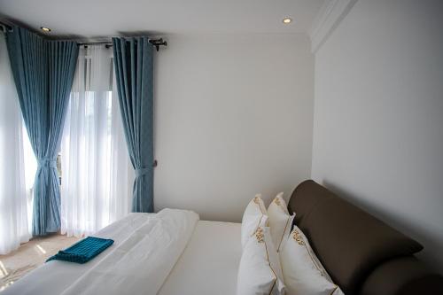 a bedroom with a white bed with blue curtains at Iris Lakeside Condos in Entebbe in Entebbe