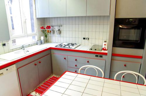 - une cuisine avec des placards rouges et blancs et une cuisinière dans l'établissement Trois Conils - Localisation exceptionnelle 3 chambres 3 salles de bain Parking, à Bordeaux