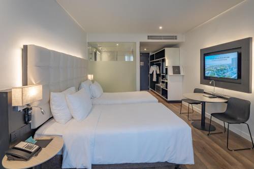 a bedroom with a large white bed and a television at Hotel Soleil Ha Long, Trademark Collection by Wyndham in Ha Long
