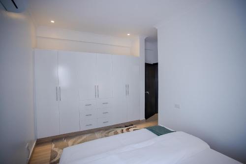 a bedroom with a white bed and a window at Iris Lakeside Condos in Entebbe in Entebbe
