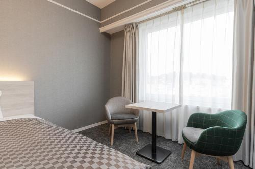 倉敷市にあるThe One Five Garden Kurashiki - Vacation STAY 96319vのベッド、テーブル、椅子が備わるホテルルームです。