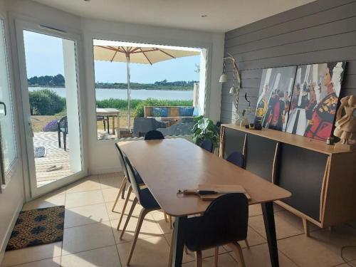 - une salle à manger avec une table, des chaises et un parasol dans l'établissement Villa de vacances au bord de mer, à l'Île-Tudy