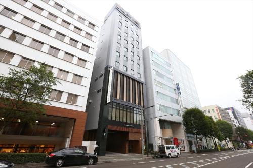 a building on a city street with cars parked in front at Almont Hotel Sendai in Sendai