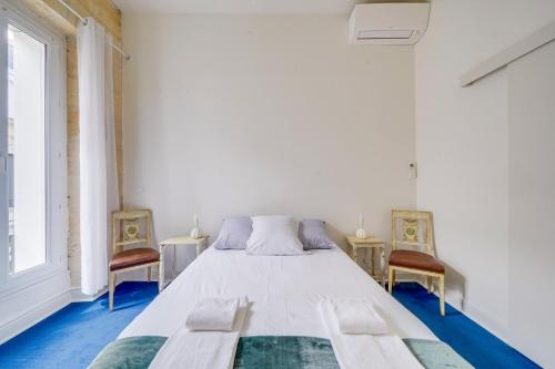 une chambre avec un lit blanc et deux chaises dans l'établissement Bel appartement proche Victoire, à Bordeaux