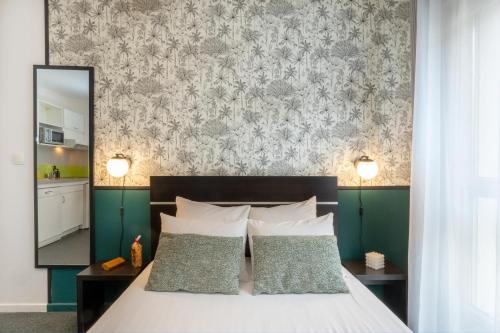 uma cama com duas almofadas e uma parede com um espelho em Nemea Appart Hotel Home Suite Nancy Centre em Nancy