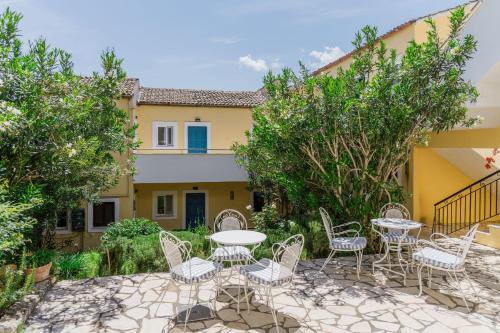 a patio with chairs and tables in front of a building at Sunflower Apartments & Studios in Kassiopi