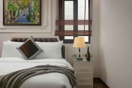 a bedroom with a bed with white sheets and a window at TrangTrang Luxury Hotel in Hanoi