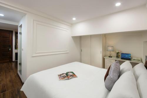 a bedroom with a white bed with a magazine on it at TrangTrang Luxury Hotel in Hanoi
