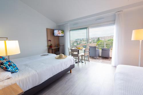 a bedroom with a bed and a table with a view at Zenitude Hôtel-Résidences Le Cannet in Le Cannet