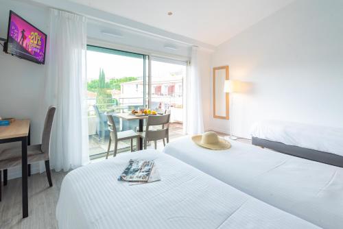 a hotel room with two beds and a table and a balcony at Zenitude Hôtel-Résidences Le Cannet in Le Cannet