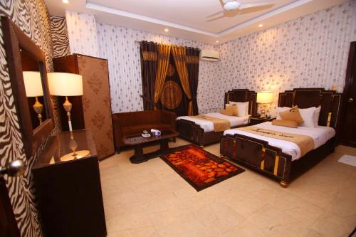 a bedroom with two beds and a chair and a couch at Premier Inn Johar Town Lahore in Lahore