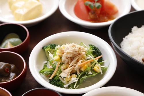 a bowl of food with broccoli and rice on a table at Dormy Inn Maebashi in Maebashi