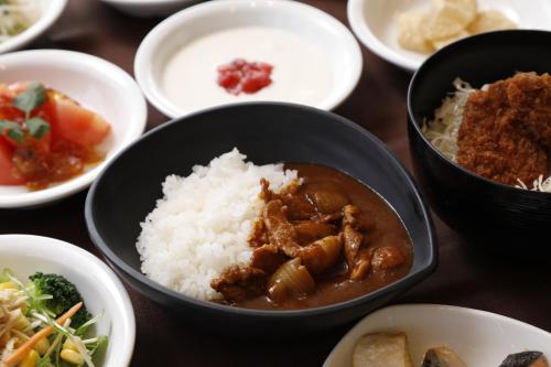 a table topped with bowls of food and rice at Dormy Inn Maebashi in Maebashi