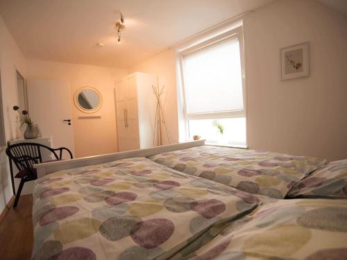 a bedroom with a bed with a flowered comforter and a window at Ferienwohnung Stadtperle Leer 15152 in Leer