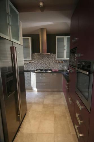 une cuisine équipée d'appareils électroménagers en acier inoxydable et de placards violets dans l'établissement Villa coup de cœur, 50 m plage et Thermes marins, à Saint-Malo