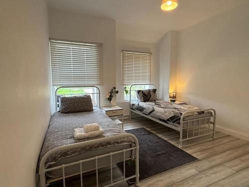 a bedroom with two beds and a window at Charming 2BR Cottage - Fully Furnished - 10min LGW - Free Parking in Crawley