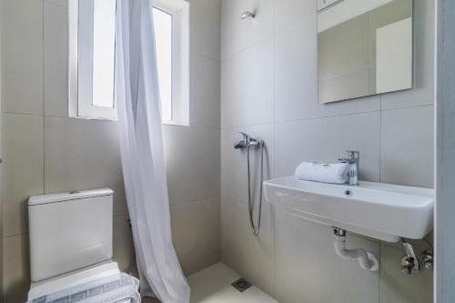 a white bathroom with a sink and a toilet at Sunflower Apartments & Studios in Kassiopi