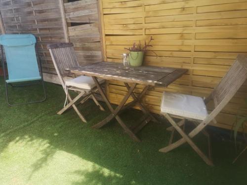 une table en bois et deux chaises assises à côté d'un mur dans l'établissement Studio indépendant dans villa avec piscine Cagnes, à Cagnes-sur-Mer