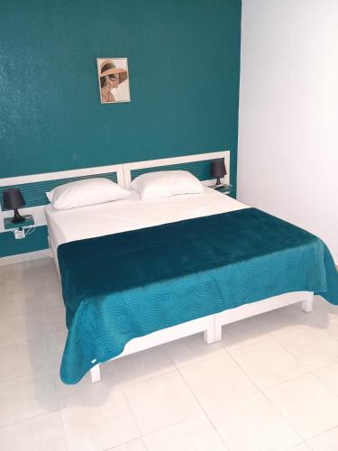 une chambre avec un grand lit avec un mur bleu dans l'établissement Les villas de Melody, à Santa-Maria-Poggio