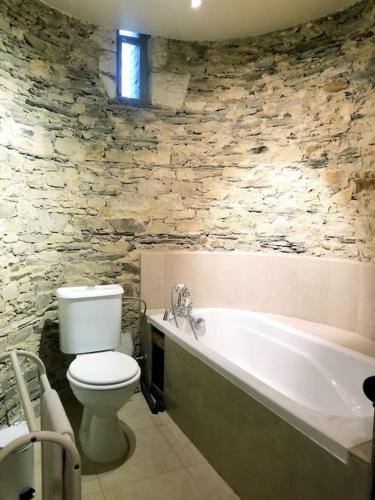 La salle de bains est pourvue de toilettes blanches et d'une baignoire. dans l'établissement Grand gîte dans les communs d'un Château, à Grand-Auverné