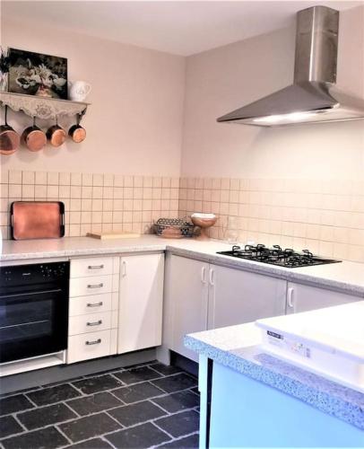 une cuisine avec des armoires blanches et un four à plaques de cuisson dans l'établissement Grand gîte dans les communs d'un Château, à Grand-Auverné