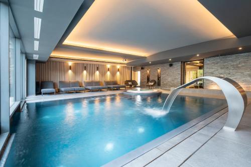 a large swimming pool in a hotel room with a swimming pooliterator at Best Western Premier Le Chapitre Hotel and Spa in Remiremont
