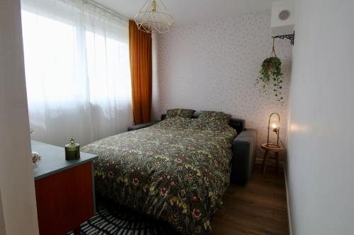 a bedroom with a bed with a comforter and a window at Le Rétro de la Gare - FloBNB in Laon