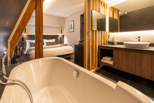 a bathroom with a bath tub and a bedroom at Best Western Premier Le Chapitre Hotel and Spa in Remiremont