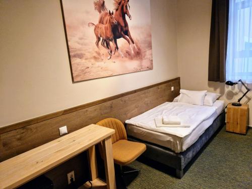 a bedroom with a bed and a painting of horses at Garda Hotel in Szombathely