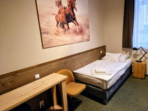 - une chambre avec un lit et une peinture de chevaux dans l'établissement Garda Hotel, à Szombathely