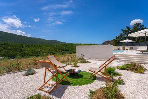 a patio with two chairs and a grill and a pool at NEW Stylish villa Tenera with private pool, 3 bedrooms in Tugare