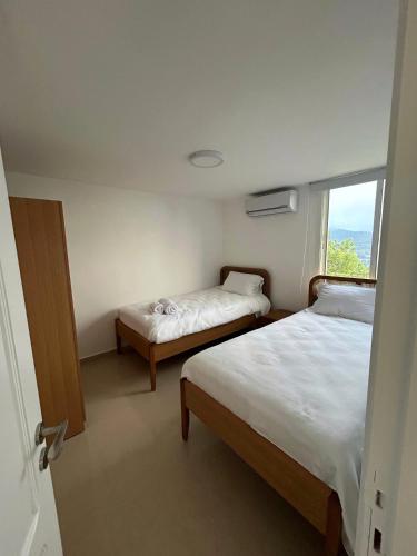 two beds in a small room with a window at Beit Mema in Aḑ Ḑahr