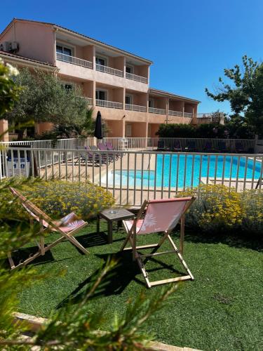 a couple of chairs and a table next to a pool at Hôtel Restaurant L' Empereur in Aléria