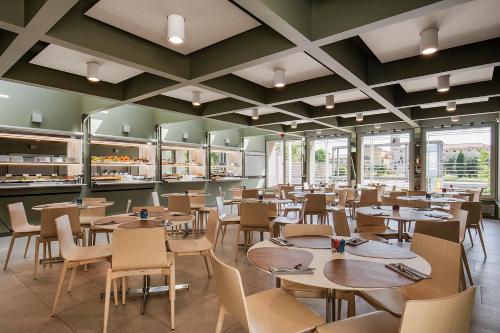 a restaurant with wooden tables and chairs and windows at Hotel Verona in Verona