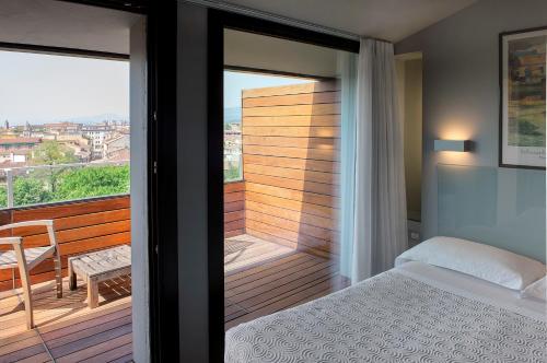 1 dormitorio con balcón con 1 cama y 1 mesa en Hotel Verona, en Verona