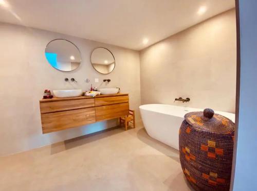 La salle de bains est pourvue d'une baignoire, d'un lavabo et de deux miroirs. dans l'établissement Maison bord de mer avec jacuzzi, à Marseille