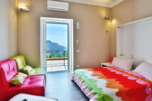 Ravello Views Apartment في رافيلو: غرفة نوم بسرير واريكة ونافذة