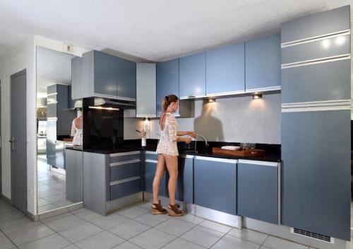 une femme debout dans une cuisine avec un évier dans l'établissement Studio Miroir - Héliopolis D 72 - Luxe - 4 personnes, au Cap d'Agde