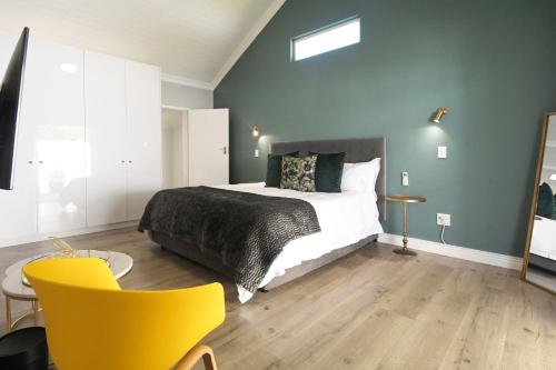 um quarto com uma cama e uma cadeira amarela em The Rose Cottage na Cidade do Cabo