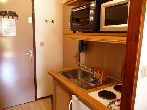 une petite cuisine avec un évier et un micro-ondes dans l'établissement Appartement face à la montagne, à Abondance