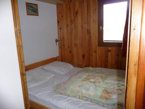 un petit lit dans une chambre avec une fenêtre dans l'établissement Appartement face à la montagne, à Abondance